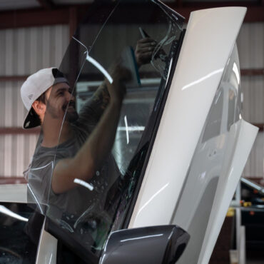 man installing window tint on white suicide car door