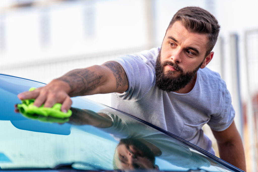 man cleaning his car with microfiber cloth